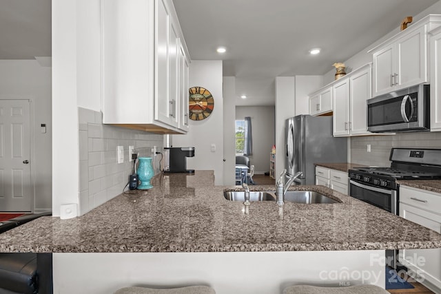 7172 Teague Dr, Gastonia, NC 28056 - kitchen featuring appliances with stainless steel finishes, a sink, a peninsula, a kitchen breakfast bar, and recessed lighting