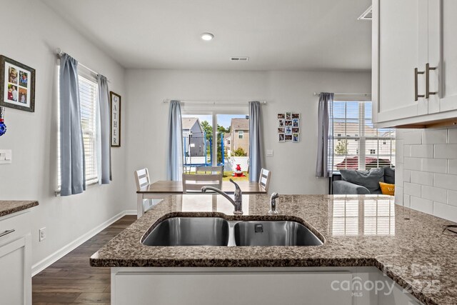 7172 Teague Dr, Gastonia, NC 28056 - kitchen featuring a sink, dark stone counters, dark wood finished floors, white cabinets, and healthy amount of natural light