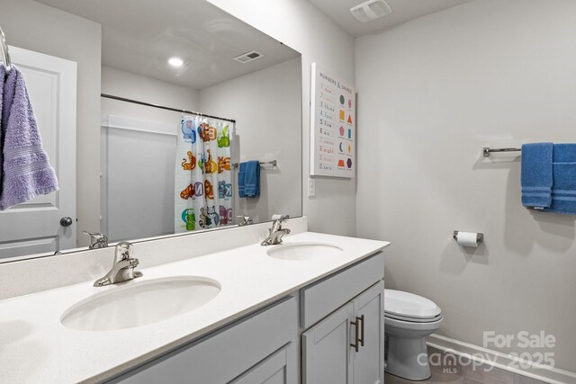 7172 Teague Dr, Gastonia, NC 28056 - bathroom featuring toilet, double vanity, baseboards, and a shower with shower curtain