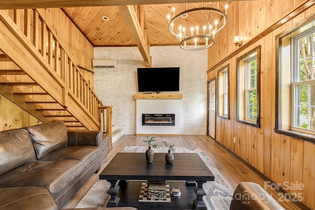 6541 Grassy Branch Rd, Bryson City, NC 28713 - living room with an AC wall unit, a wood ceiling with exposed beams, light wood finished floors, a glass covered fireplace, and a chandelier