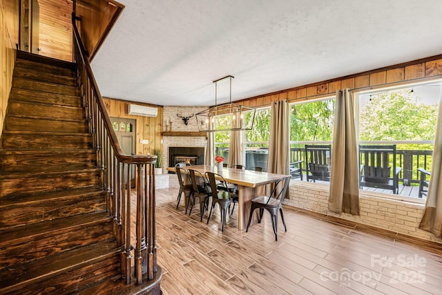6541 Grassy Branch Rd, Bryson City, NC 28713 - dining area featuring an AC wall unit, wooden walls, stairs, a brick fireplace, and wood finished floors
