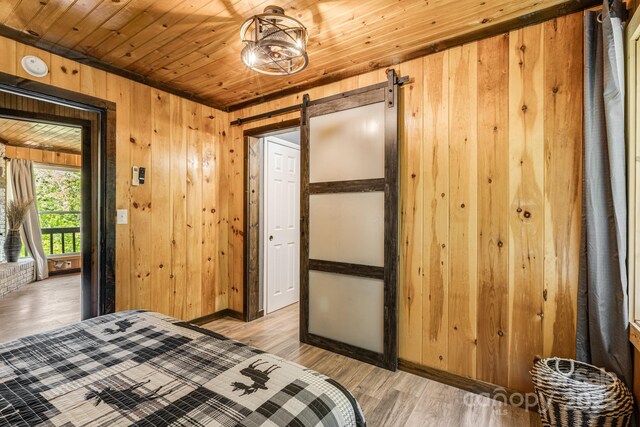 6541 Grassy Branch Rd, Bryson City, NC 28713 - bedroom with wooden walls, light wood-type flooring, a barn door, and wooden ceiling