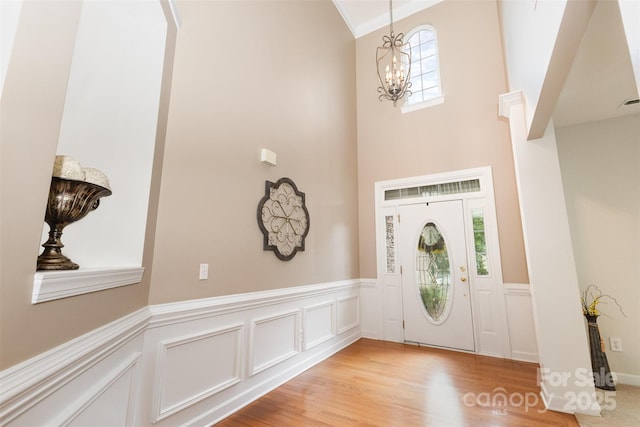 9814 Tompkins Ln, Waxhaw, NC 28173 - foyer entrance with a chandelier, wainscoting, light wood-style floors, a decorative wall, and a towering ceiling