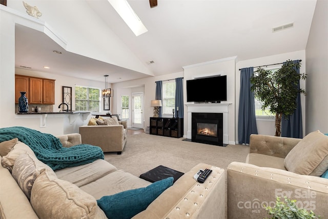 9814 Tompkins Ln, Waxhaw, NC 28173 - living area featuring light colored carpet, a chandelier, a fireplace with flush hearth, a skylight, and high vaulted ceiling
