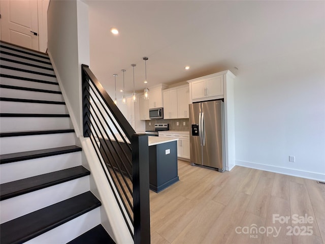6013 Countess Dr Unit 51, Charlotte, NC 28217 - kitchen featuring stainless steel appliances, white cabinets, light wood-style floors, tasteful backsplash, and recessed lighting