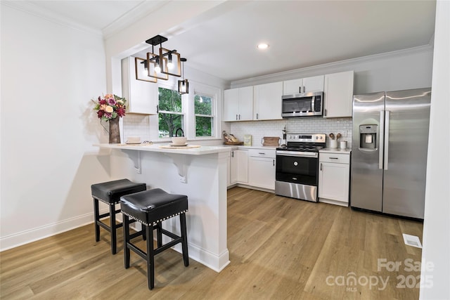 940 N New Hope Rd, Gastonia, NC 28054 - kitchen featuring stainless steel appliances, ornamental molding, a breakfast bar, a peninsula, and light wood-style floors