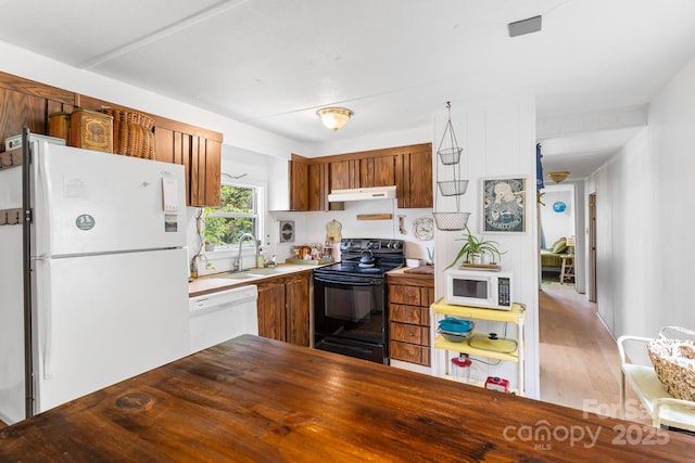 355 Dix Creek Rd, Leicester, NC 28748 - kitchen with white appliances, under cabinet range hood, a sink, wood finished floors, and brown cabinets
