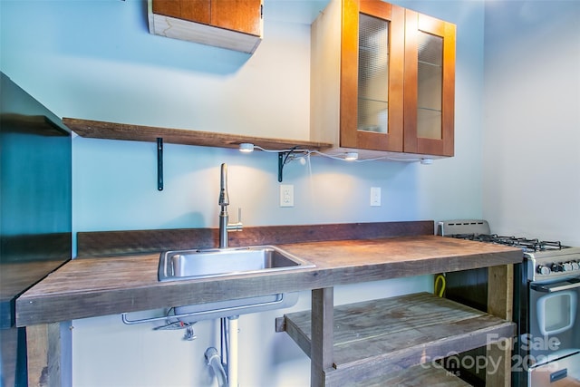 1146 Thomas Branch Rd, Marshall, NC 28753 - kitchen with stainless steel range with gas cooktop, a sink, butcher block countertops, glass insert cabinets, and brown cabinets