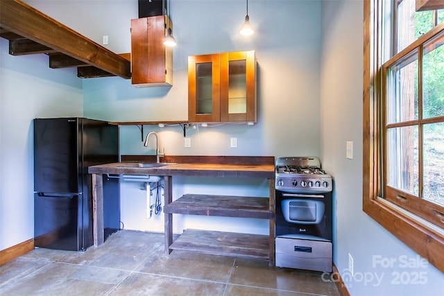 1146 Thomas Branch Rd, Marshall, NC 28753 - kitchen featuring freestanding refrigerator, stainless steel gas stove, a sink, baseboards, and glass insert cabinets