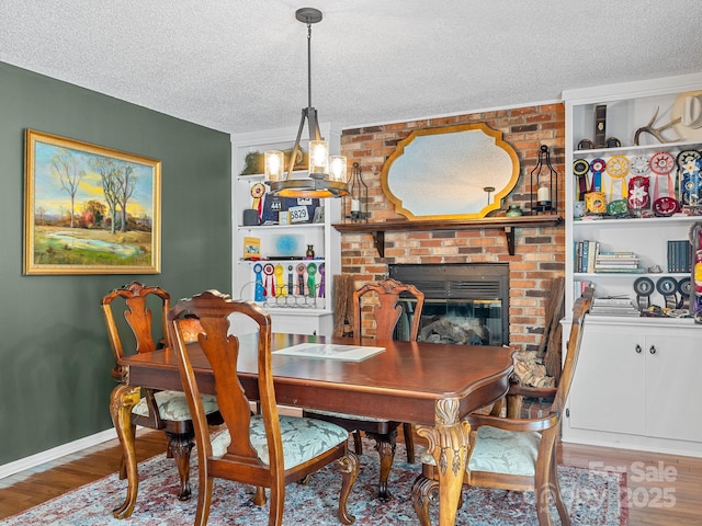192 Shady Ln, Mill Spring, NC 28756 - dining space featuring a textured ceiling, wood finished floors, a chandelier, and a fireplace