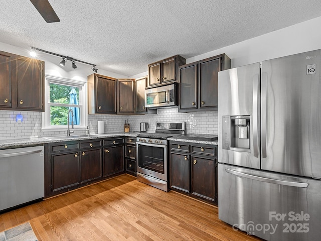 192 Shady Ln, Mill Spring, NC 28756 - kitchen with stainless steel appliances, a textured ceiling, light wood-type flooring, tasteful backsplash, and light stone countertops