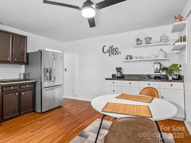 192 Shady Ln, Mill Spring, NC 28756 - kitchen featuring stainless steel refrigerator with ice dispenser, dark brown cabinetry, light wood-type flooring, tasteful backsplash, and a textured ceiling