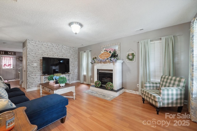 1912 8th St SE, Hickory, NC 28602 - living room with a fireplace with raised hearth, wood finished floors, a textured ceiling, and baseboards