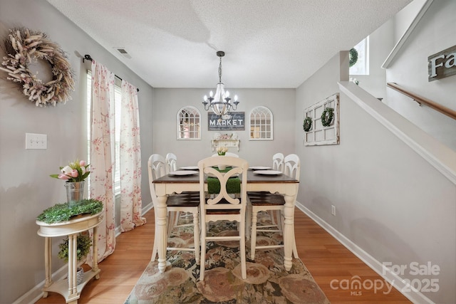 1912 8th St SE, Hickory, NC 28602 - dining area featuring light wood-style floors, a chandelier, a textured ceiling, and baseboards