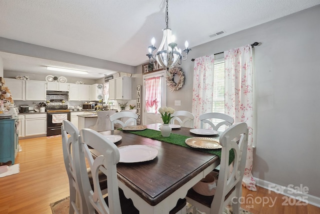 1912 8th St SE, Hickory, NC 28602 - dining room featuring light wood-style floors, a chandelier, a textured ceiling, and baseboards