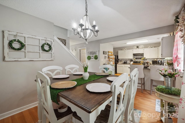 1912 8th St SE, Hickory, NC 28602 - dining room with light wood-type flooring, a chandelier, baseboards, and stairway