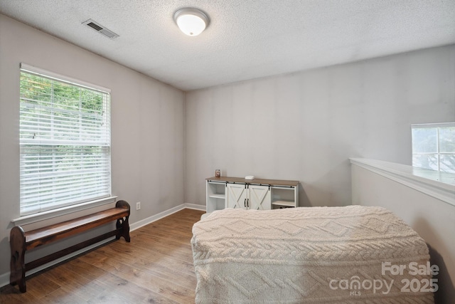1912 8th St SE, Hickory, NC 28602 - bedroom featuring wood finished floors, multiple windows, a textured ceiling, and baseboards