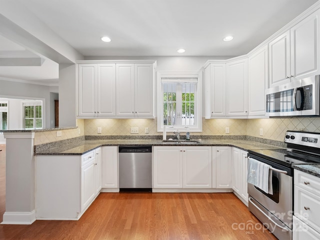 10875 Casetta Dr, Matthews, NC 28105 - kitchen with appliances with stainless steel finishes, plenty of natural light, light wood-type flooring, a peninsula, and recessed lighting