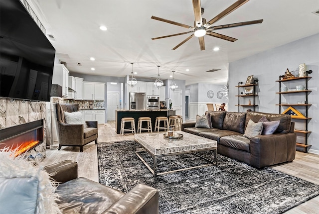 7809 Creek Park Dr, Denver, NC 28037 - living room with ceiling fan, light wood-style flooring, recessed lighting, a tiled fireplace, and a chandelier