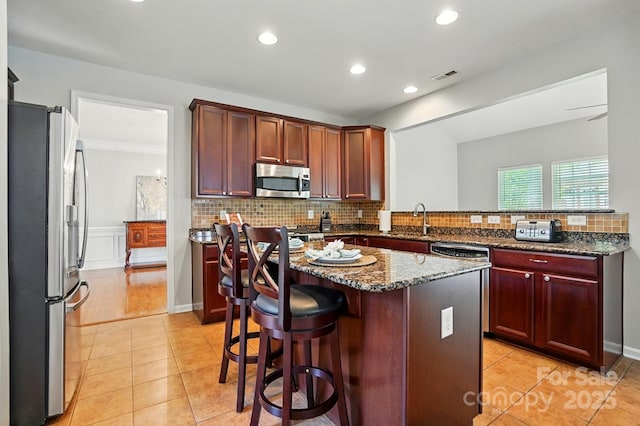 415 Glandon Ct, Fort Mill, SC 29708 - kitchen featuring appliances with stainless steel finishes, a sink, decorative backsplash, a kitchen island, and light tile patterned flooring