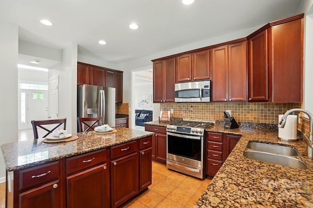 415 Glandon Ct, Fort Mill, SC 29708 - kitchen with appliances with stainless steel finishes, a sink, reddish brown cabinets, backsplash, and a center island