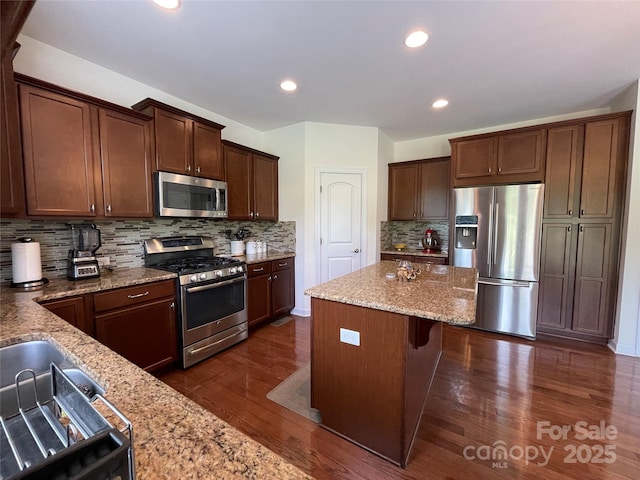 707 Five Leaf Ln, Waxhaw, NC 28173 - kitchen featuring stainless steel appliances, decorative backsplash, light stone countertops, a center island, and dark wood-type flooring
