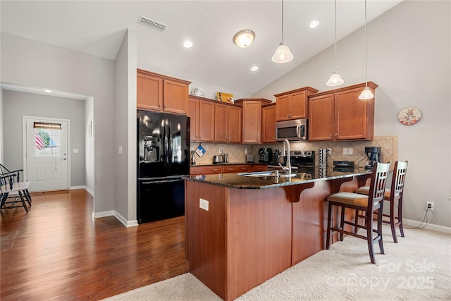 25566 Seagull Dr, Lancaster, SC 29720 - kitchen with stainless steel appliances, a peninsula, a sink, dark stone countertops, and brown cabinetry