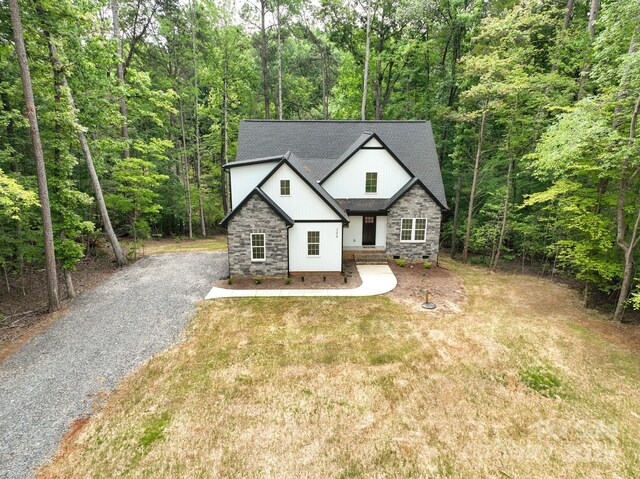 248 Pioneer Dr, Mount Gilead, NC 27306 - view of front of house with a view of trees, stone siding, and a shingled roof