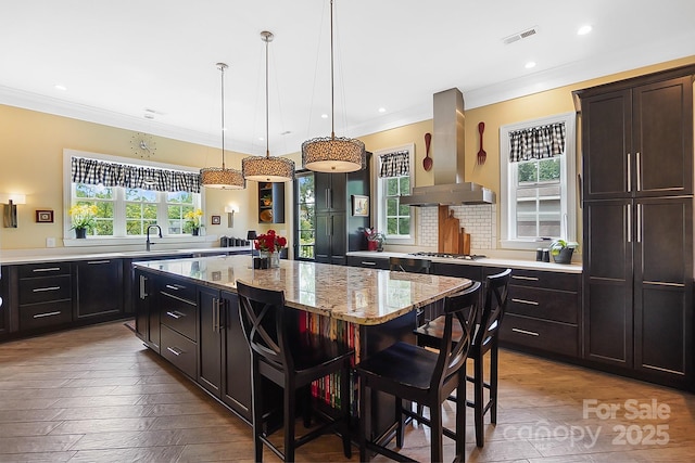 2354 Valelake Rd, York, SC 29745 - kitchen with wall chimney range hood, a center island, ornamental molding, light stone counters, and stainless steel gas cooktop