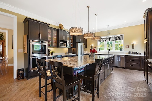 2354 Valelake Rd, York, SC 29745 - kitchen featuring stainless steel appliances, light wood-type flooring, a breakfast bar area, dark brown cabinetry, and ornamental molding