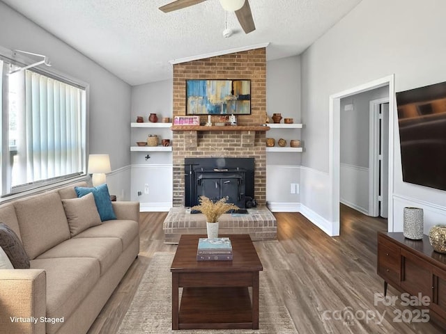 2316 Woodfield Cir, Gastonia, NC 28056 - living area with a textured ceiling, wood finished floors, vaulted ceiling, ceiling fan, and a brick fireplace