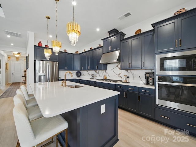 6015 Waldorf Ave, Monroe, NC 28110 - kitchen featuring stainless steel appliances, a sink, under cabinet range hood, a chandelier, and a kitchen bar
