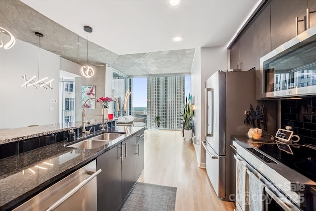 210 N Church St Unit 2807, Charlotte, NC 28202 - kitchen with a sink, stainless steel appliances, light wood-style floors, dark stone countertops, and floor to ceiling windows
