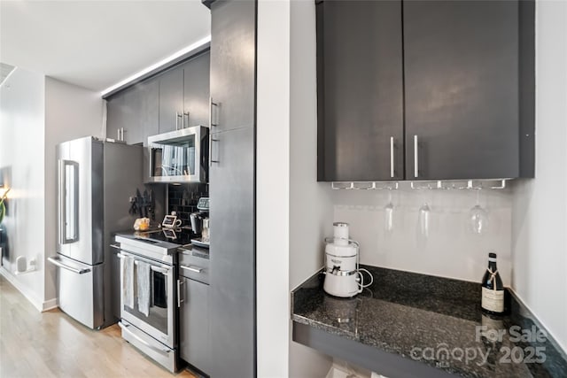 210 N Church St Unit 2807, Charlotte, NC 28202 - kitchen featuring stainless steel appliances, light wood-style floors, tasteful backsplash, and dark stone counters