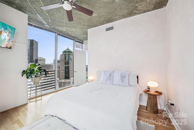 210 N Church St Unit 2807, Charlotte, NC 28202 - bedroom with wood finished floors, floor to ceiling windows, a ceiling fan, baseboards, and a city view