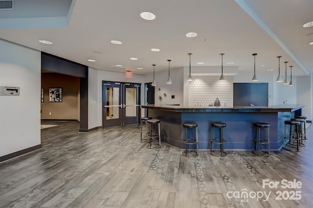 210 N Church St Unit 2807, Charlotte, NC 28202 - kitchen featuring dark countertops, wood finished floors, decorative backsplash, a breakfast bar, and recessed lighting