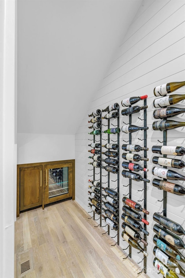 4211 Tangle Dr, Charlotte, NC 28211 - wine room featuring vaulted ceiling, light wood-style floors, and wooden walls