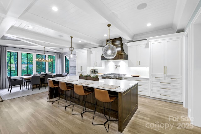 4211 Tangle Dr, Charlotte, NC 28211 - kitchen with light wood finished floors, a spacious island, white cabinetry, a kitchen breakfast bar, and custom exhaust hood