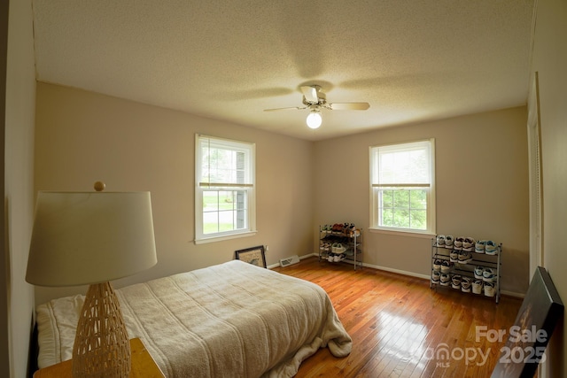 1867 Shannon Dr, Conover, NC 28613 - bedroom featuring multiple windows, hardwood / wood-style floors, baseboards, a textured ceiling, and a ceiling fan
