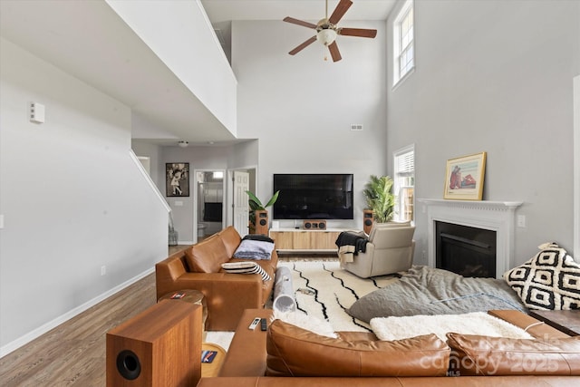 197 Roanoke Rd, Fletcher, NC 28732 - living area featuring a ceiling fan, a fireplace, a towering ceiling, plenty of natural light, and light wood-style floors
