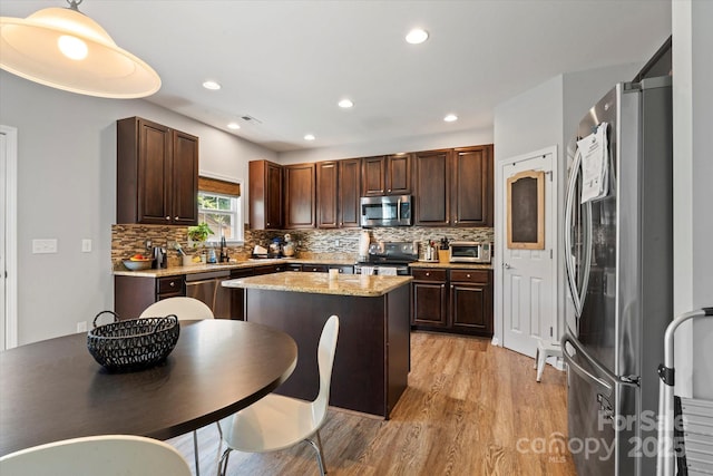 197 Roanoke Rd, Fletcher, NC 28732 - kitchen with stainless steel appliances, light wood-type flooring, a kitchen island, dark brown cabinets, and decorative backsplash
