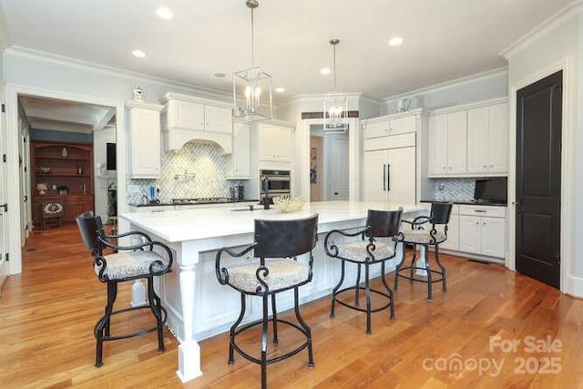 1103 Mapesbury Ln, Waxhaw, NC 28173 - kitchen featuring oven, tasteful backsplash, crown molding, white cabinetry, and decorative light fixtures