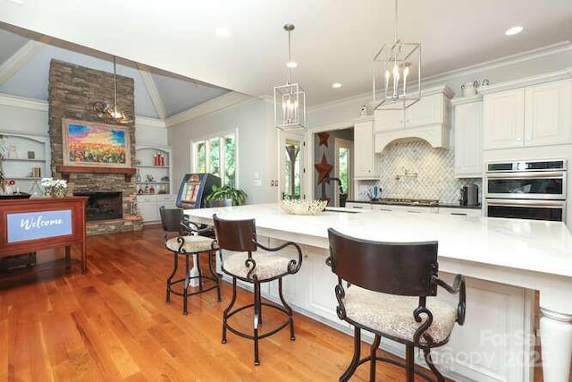 1103 Mapesbury Ln, Waxhaw, NC 28173 - kitchen with double oven, ornamental molding, a sink, light wood-style floors, and a stone fireplace