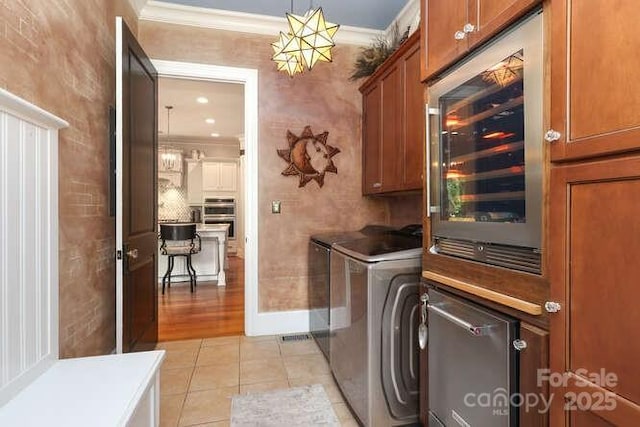 1103 Mapesbury Ln, Waxhaw, NC 28173 - laundry room featuring cabinet space, washing machine and clothes dryer, crown molding, beverage cooler, and light tile patterned floors