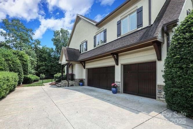 1103 Mapesbury Ln, Waxhaw, NC 28173 - view of side of property with stucco siding, an attached garage, concrete driveway, and stone siding