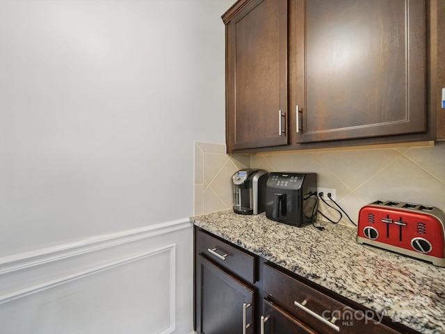 11225 Island View Ln, Lancaster, SC 29720 - kitchen featuring dark brown cabinetry, decorative backsplash, light stone countertops, and a wainscoted wall