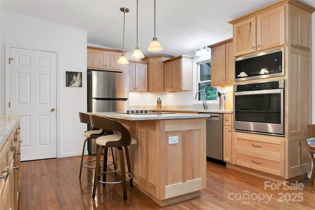 500 Cheestoonaya Way, Brevard, NC 28712 - kitchen featuring appliances with stainless steel finishes, light brown cabinetry, hardwood / wood-style flooring, a kitchen island, and a breakfast bar