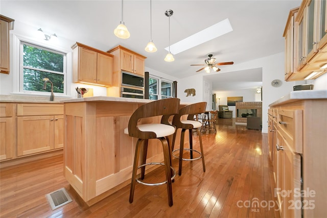 500 Cheestoonaya Way, Brevard, NC 28712 - kitchen featuring light brown cabinetry, a skylight, a fireplace, light wood-style flooring, and lofted ceiling