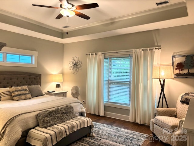 1636 Sand Harbor Cir, Ocean Isle Beach, NC 28469 - bedroom featuring dark wood finished floors, multiple windows, a tray ceiling, and a ceiling fan
