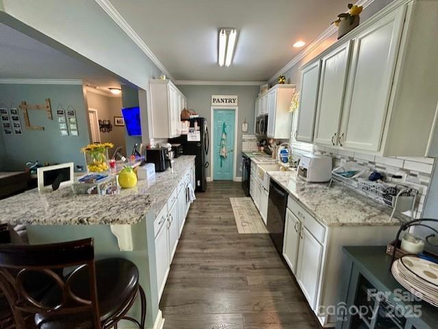 1545 Lewis Farm Rd, Kings Mountain, NC 28086 - kitchen with stainless steel microwave, dishwasher, dark wood-type flooring, ornamental molding, and a breakfast bar